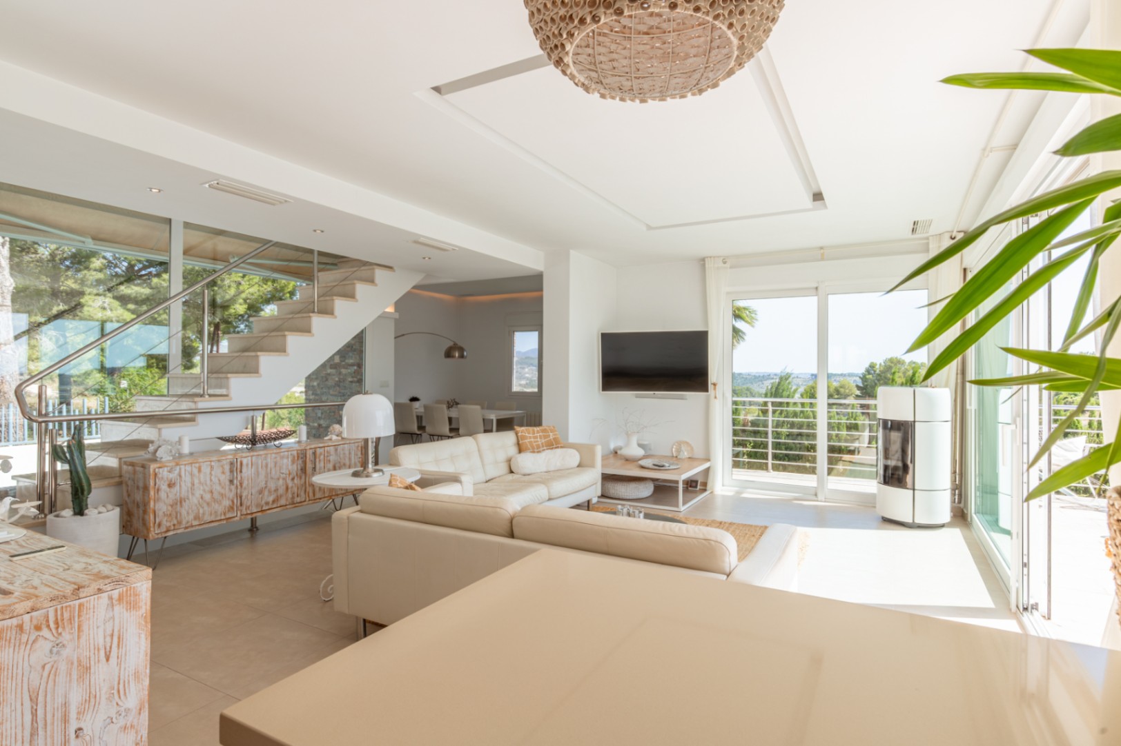 Amplio salón diáfano con sofá crema, estufa de pellets y balcón con vistas. Destacan la escalera de diseño con barandilla de acero y un mueble rústico. Amplio salón diáfano con sofá crema, estufa de pellets y balcón con vistas. Destacan la escalera de diseño con barandilla de acero y un mueble rústico.