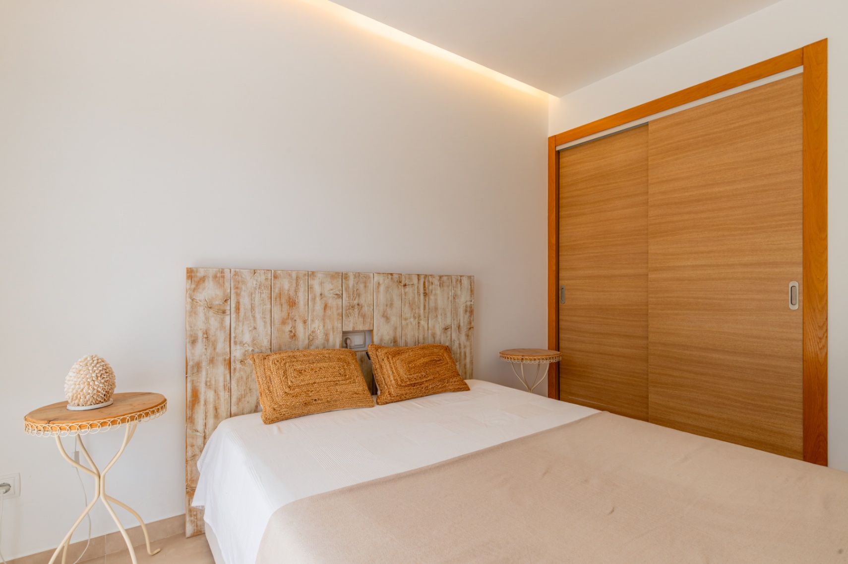 Dormitorio con cabecero de madera envejecida, armario empotrado de puertas correderas de madera clara y luz indirecta en techo. Dormitorio con cabecero de madera envejecida, armario empotrado de puertas correderas de madera clara y luz indirecta en techo.