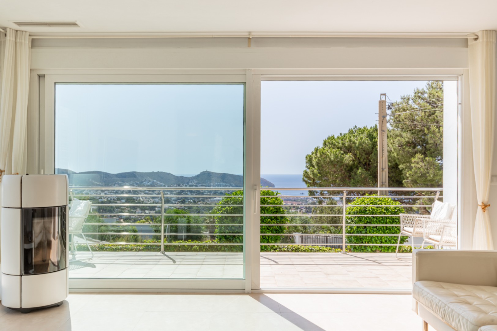 Luminosa zona de día con estufa de pellets y amplios ventanales correderos que acceden a una terraza con vistas al mar y la costa. Luminosa zona de día con estufa de pellets y amplios ventanales correderos que acceden a una terraza con vistas al mar y la costa.