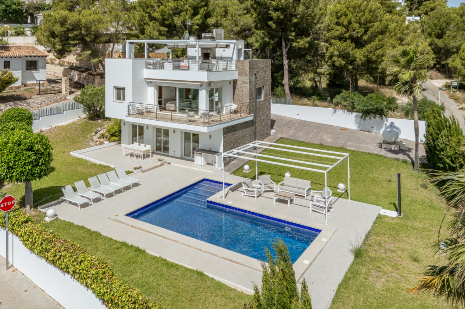 Vista aérea de la villa moderna de varios niveles con piscina rectangular, amplias terrazas con zonas de estar y comedor, y césped cuidado, rodeada de exuberante vegetación. Vista aérea de la villa moderna de varios niveles con piscina rectangular, amplias terrazas con zonas de estar y comedor, y césped cuidado, rodeada de exuberante vegetación.