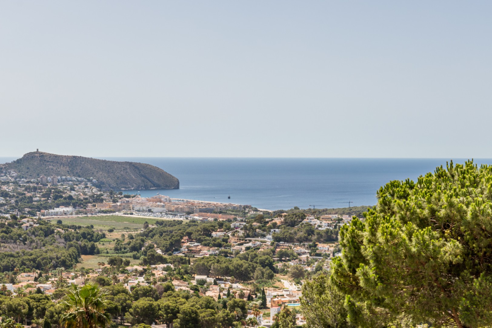 Vista elevada de Moraira desde Benimeit, mostrando el Cap d'Or, el litoral mediterráneo y la extensión residencial arbolada. Vista elevada de Moraira desde Benimeit, mostrando el Cap d'Or, el litoral mediterráneo y la extensión residencial arbolada.