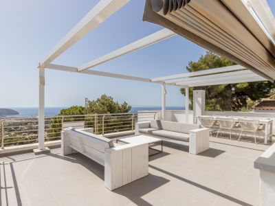 Amplio solárium en la azotea con pérgola blanca, toldo automatizado y zona chill-out con vistas panorámicas al mar.