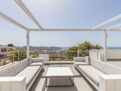 Solárium en la azotea con pérgola blanca, dos sofás exteriores y una mesa de centro, enmarcando vistas panorámicas del mar Mediterráneo y la costa.