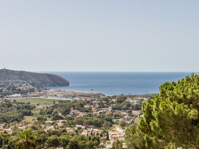 Vista elevada de Moraira desde Benimeit, mostrando el Cap d'Or, el litoral mediterráneo y la extensión residencial arbolada.
