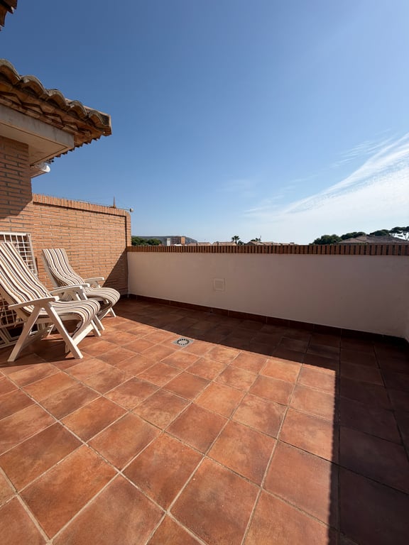 Amplia terraza superior con suelo de baldosas de terracota y pared de ladrillo. Equipada con dos tumbonas, ofrece un espacio soleado y abierto con vistas despejadas. Amplia terraza superior con suelo de baldosas de terracota y pared de ladrillo. Equipada con dos tumbonas, ofrece un espacio soleado y abierto con vistas despejadas.