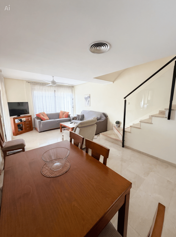 Amplio salón-comedor de planta abierta con mesa de madera, cómodos sofás y escalera moderna con barandilla de cristal. Aire acondicionado por conductos y suelos de baldosas. Amplio salón-comedor de planta abierta con mesa de madera, cómodos sofás y escalera moderna con barandilla de cristal. Aire acondicionado por conductos y suelos de baldosas.