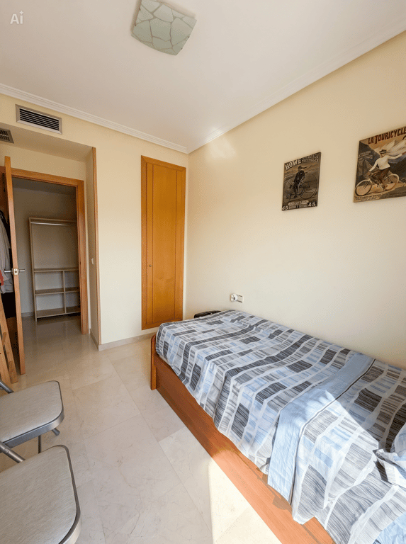 Dormitorio individual con cama de madera, suelo de mármol claro y armario empotrado. Incluye acceso a un vestidor abierto y ventilación de aire acondicionado. Dormitorio individual con cama de madera, suelo de mármol claro y armario empotrado. Incluye acceso a un vestidor abierto y ventilación de aire acondicionado.