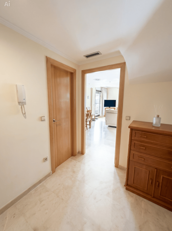 Luminoso recibidor con suelo de mármol pulido y puertas de madera clara. Un mueble auxiliar de madera se sitúa a la derecha, con vistas al salón-comedor. Luminoso recibidor con suelo de mármol pulido y puertas de madera clara. Un mueble auxiliar de madera se sitúa a la derecha, con vistas al salón-comedor.
