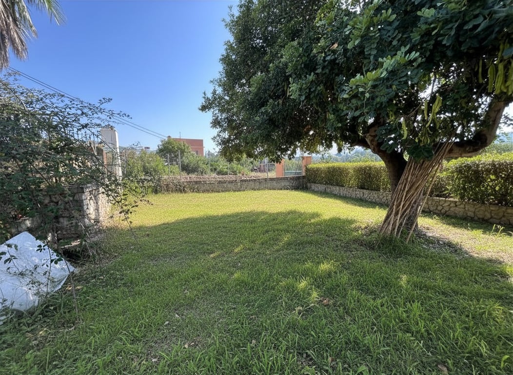 Amplio jardín privado con césped irregular y un gran árbol maduro que ofrece sombra natural. Rodeado por un muro de piedra y setos, ideal para paisajismo. Amplio jardín privado con césped irregular y un gran árbol maduro que ofrece sombra natural. Rodeado por un muro de piedra y setos, ideal para paisajismo.
