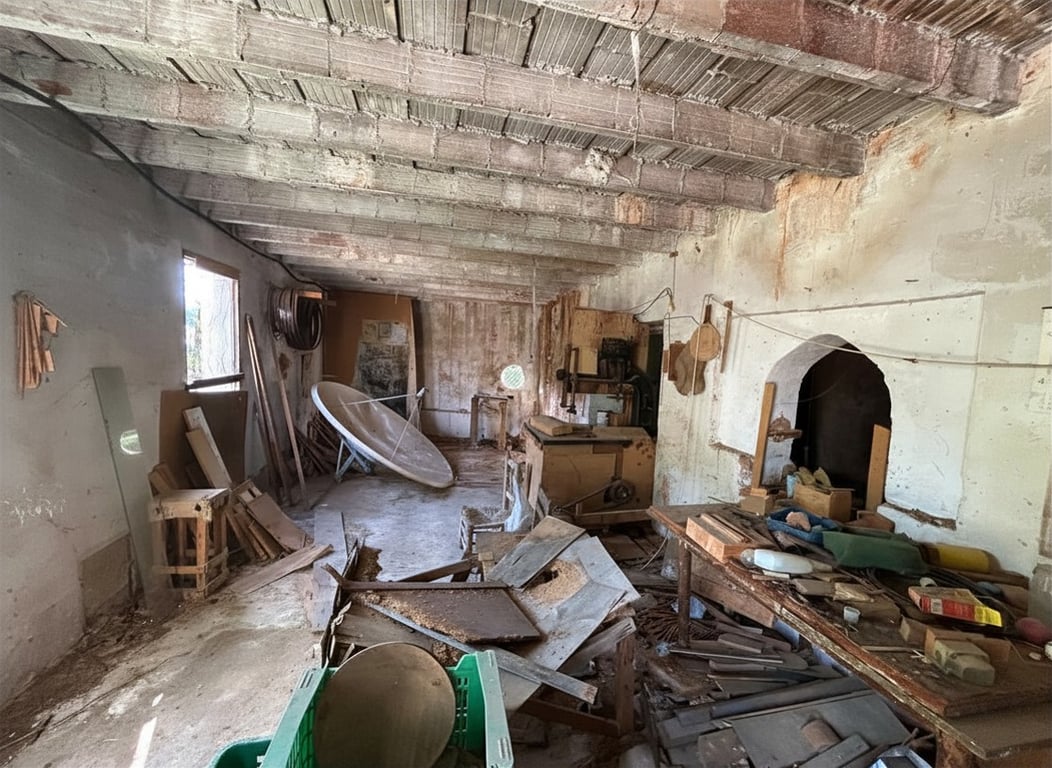 Espacio interior en bruto con techo de vigas de hormigón expuestas, paredes descascarilladas y un nicho arqueado, ideal para reforma. El área contiene escombros y maquinaria antigua. Espacio interior en bruto con techo de vigas de hormigón expuestas, paredes descascarilladas y un nicho arqueado, ideal para reforma. El área contiene escombros y maquinaria antigua.