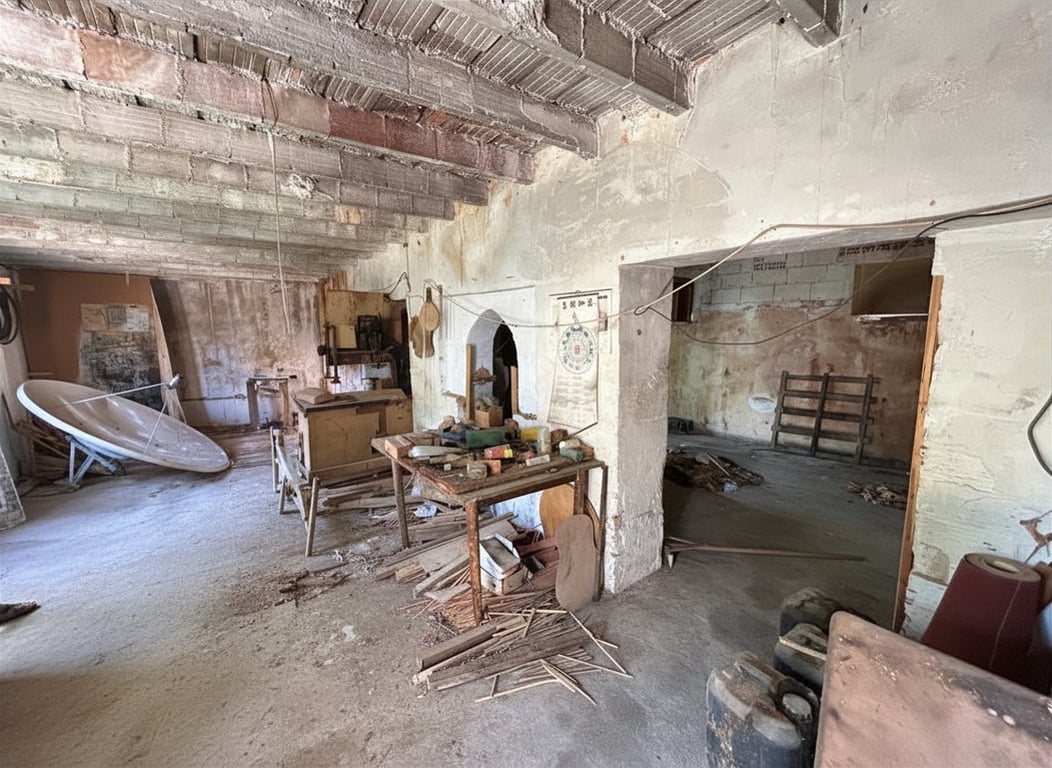 Este espacio interior en bruto muestra vigas de ladrillo y hormigón expuestas, paredes sin revocar y un suelo de hormigón con escombros. Resalta la necesidad de una reforma estructural integral. Este espacio interior en bruto muestra vigas de ladrillo y hormigón expuestas, paredes sin revocar y un suelo de hormigón con escombros. Resalta la necesidad de una reforma estructural integral.