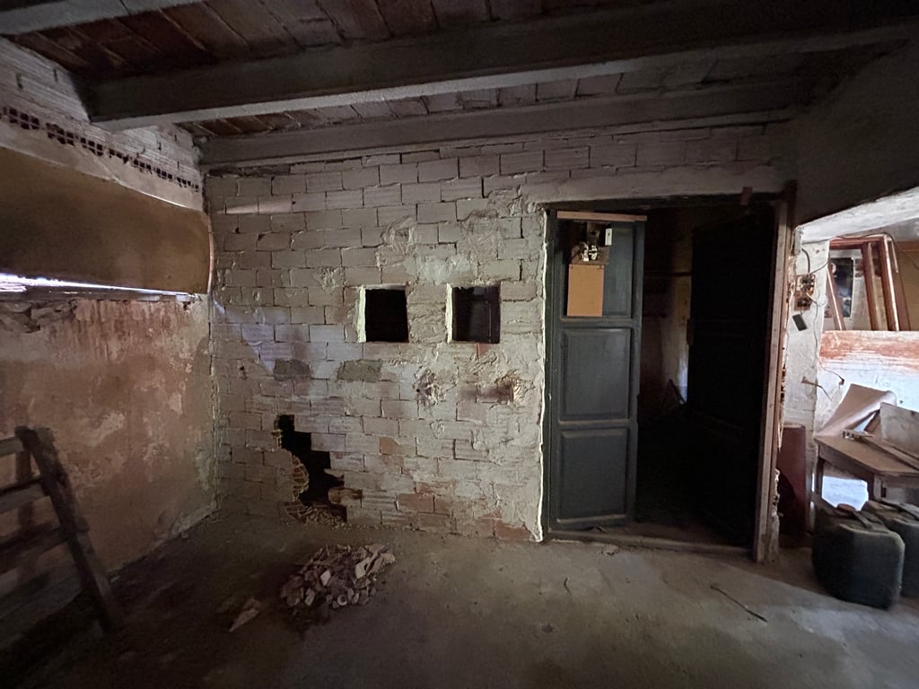 Interior en bruto con paredes de ladrillo visto, techo de vigas de madera y aberturas. Un espacio con potencial para una reforma integral, mostrando su estado actual. Interior en bruto con paredes de ladrillo visto, techo de vigas de madera y aberturas. Un espacio con potencial para una reforma integral, mostrando su estado actual.