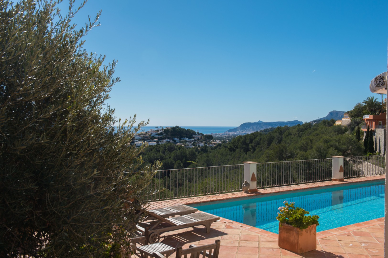 Terraza de baldosas de barro con piscina rectangular y vistas despejadas al mar Mediterráneo, el Peñón de Ifach y el entorno natural de pinos.