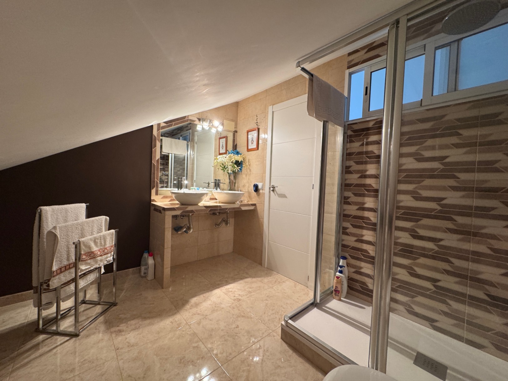 Cuarto de baño con lavabo doble sobre encimera y ducha con mampara corredera.