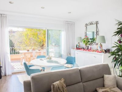 Luminoso salón-comedor con acceso directo a una terraza privada equipada con mobiliario exterior. Grandes puertas correderas de cristal ofrecen luz natural y vistas a los árboles.