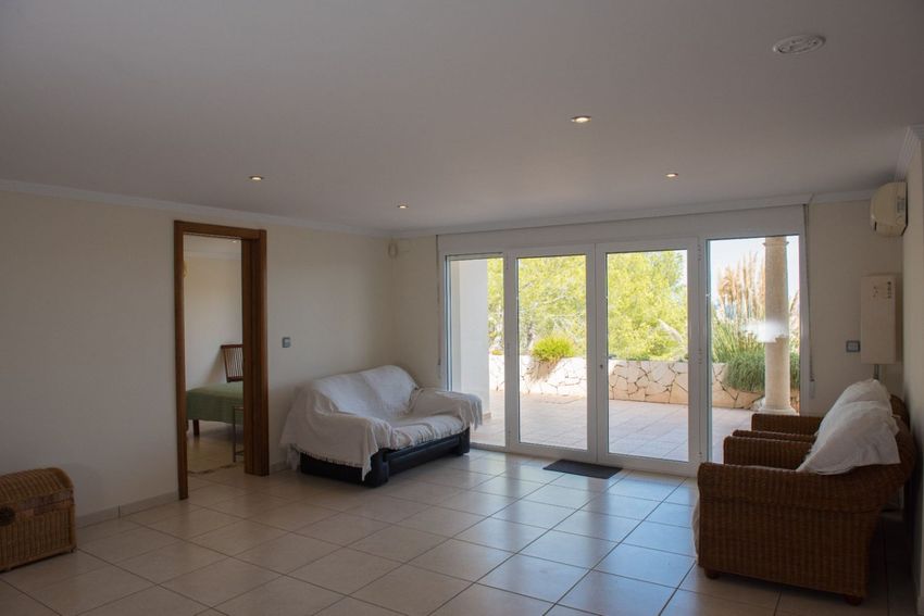 Salón con suelo de baldosas claras y focos empotrados, con amplias puertas de cristal que acceden a una terraza de piedra y vegetación mediterránea. Dispone de aire acondicionado. Salón con suelo de baldosas claras y focos empotrados, con amplias puertas de cristal que acceden a una terraza de piedra y vegetación mediterránea. Dispone de aire acondicionado.