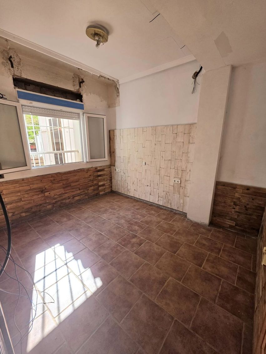 Espacio en fase de actualización con suelo de baldosas terracota y dos tipos de paneles decorativos de madera en las paredes. Ventana con persiana y abundante luz natural. Espacio en fase de actualización con suelo de baldosas terracota y dos tipos de paneles decorativos de madera en las paredes. Ventana con persiana y abundante luz natural.