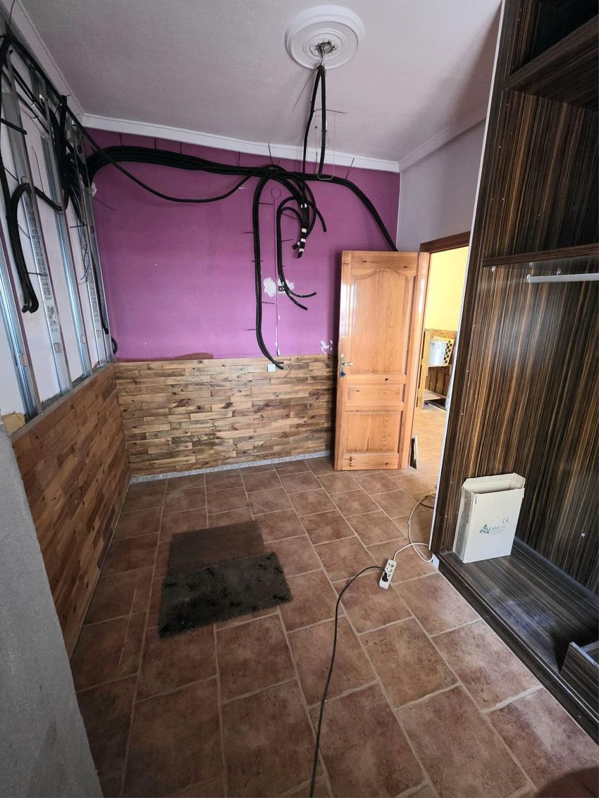 Espacio en proceso de reforma con paredes en tonos malva, revestimiento de lamas de madera y estructura metálica. Destacan las instalaciones eléctricas expuestas y el suelo de gres cerámico. Espacio en proceso de reforma con paredes en tonos malva, revestimiento de lamas de madera y estructura metálica. Destacan las instalaciones eléctricas expuestas y el suelo de gres cerámico.