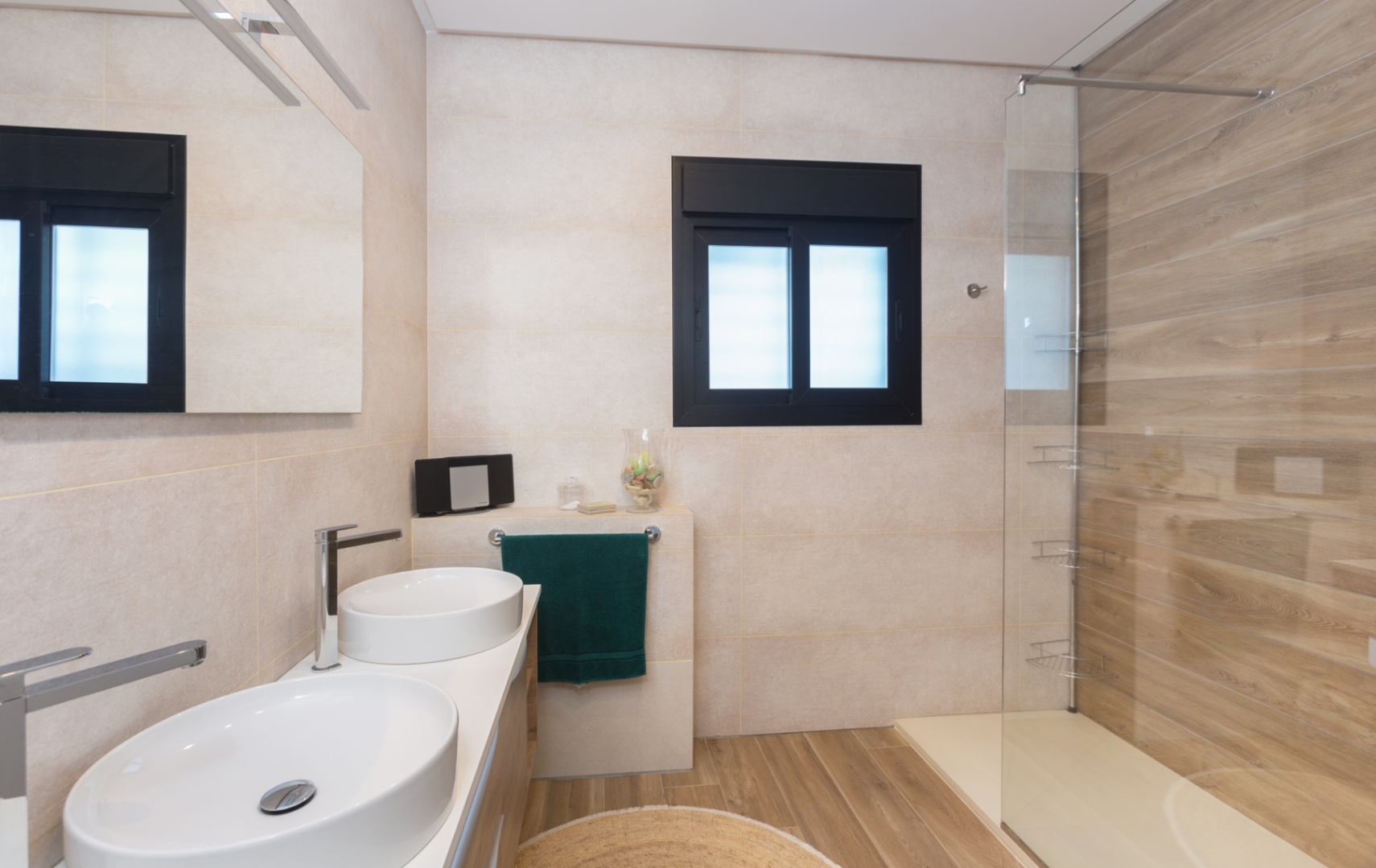 Baño moderno con doble lavabo ovalado, grifería cromada y espejo iluminado. Ducha de obra con mampara de cristal, pared de azulejos efecto madera y suelo de gres porcelánico a juego. Baño moderno con doble lavabo ovalado, grifería cromada y espejo iluminado. Ducha de obra con mampara de cristal, pared de azulejos efecto madera y suelo de gres porcelánico a juego.
