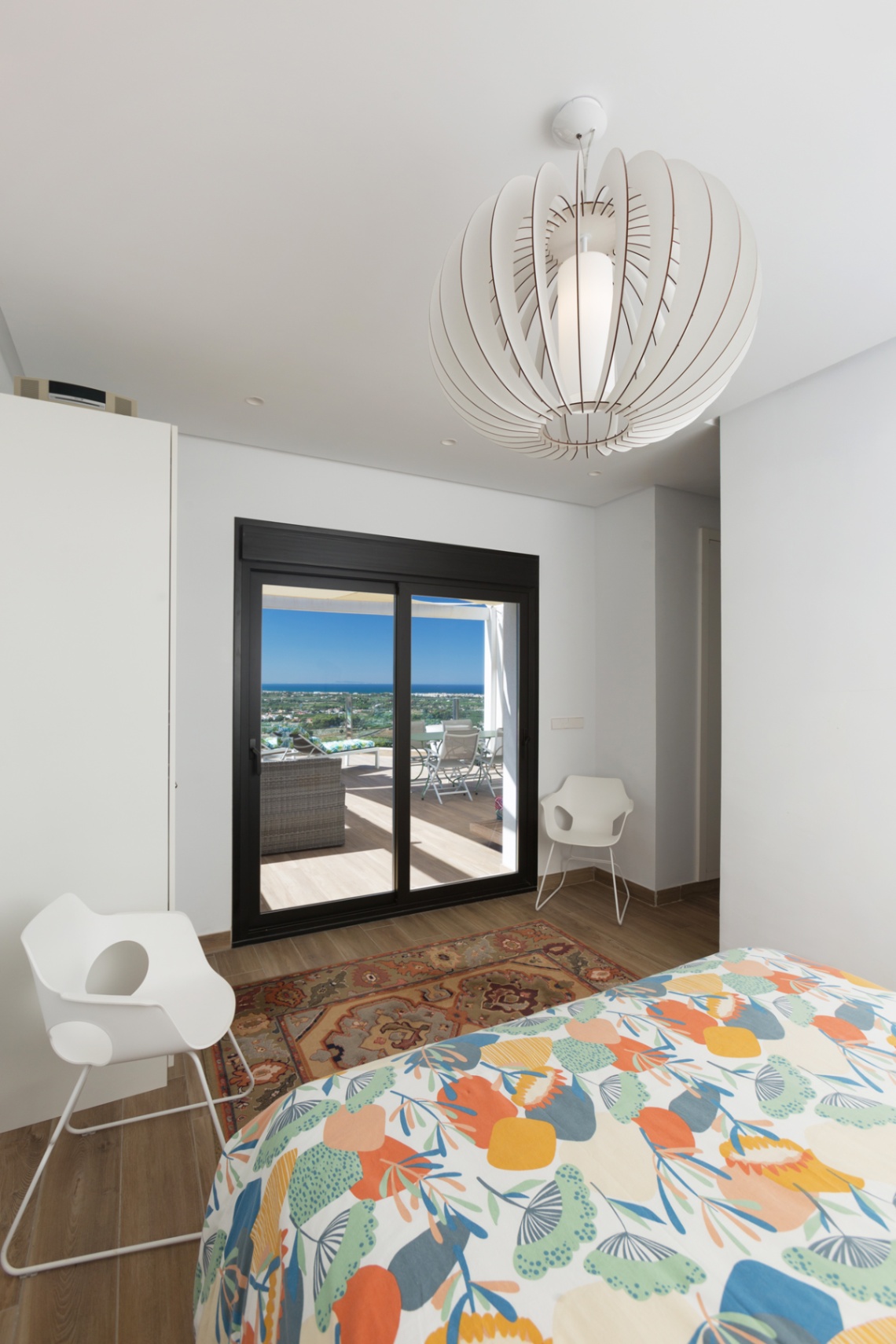 Dormitorio luminoso con acceso directo a una terraza privada, ofreciendo vistas panorámicas al paisaje. Destaca una lámpara de diseño esférico y mobiliario moderno. Dormitorio luminoso con acceso directo a una terraza privada, ofreciendo vistas panorámicas al paisaje. Destaca una lámpara de diseño esférico y mobiliario moderno.