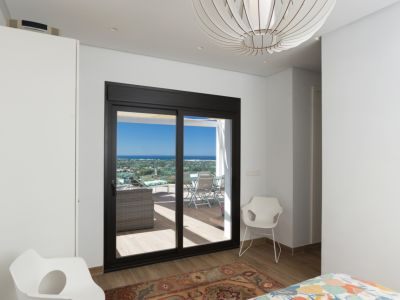 Dormitorio luminoso con acceso directo a una terraza privada, ofreciendo vistas panorámicas al paisaje. Destaca una lámpara de diseño esférico y mobiliario moderno.