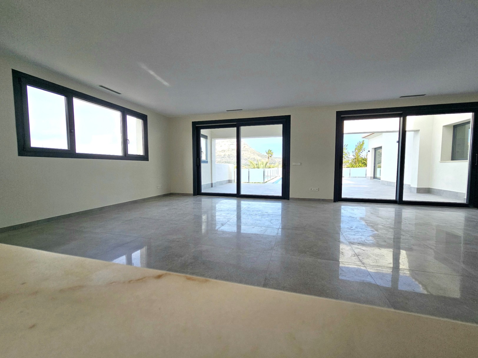 Amplio salón con suelo de gres porcelánico y acceso a la terraza exterior a través de grandes puertas correderas.