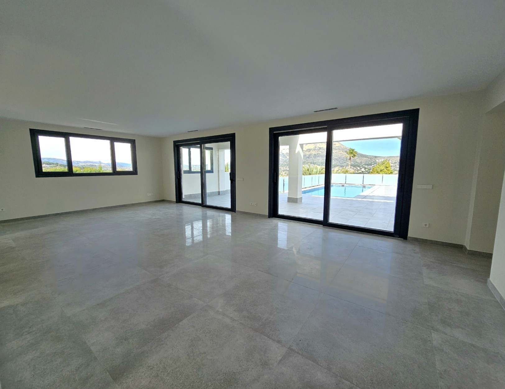Amplio salón con suelos de gres y acceso a la terraza con piscina y vistas al Montgó.