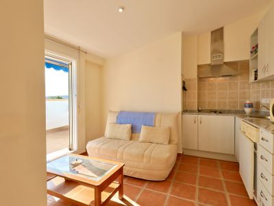 Salón-cocina diáfano con sofá y mesa de centro de madera. Suelos de baldosas de terracota, cocina equipada con campana extractora y encimera de granito, y acceso a terraza.