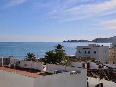 Vista panorámica del Mediterráneo desde la propiedad, mostrando el mar azul, tejados de terracota y palmeras, con la costa montañosa a lo lejos.