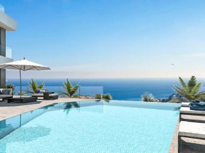 Vista de la piscina infinita con mosaicos azules y tumbonas con vistas al mar.