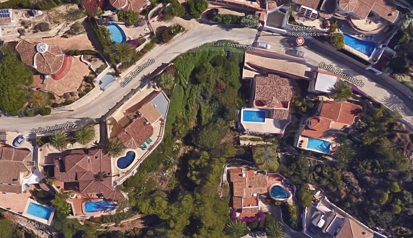 Vista aérea de parcela en Benimeit, Moraira, rodeada de villas con piscinas y vegetación.