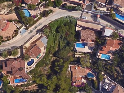 Vista aérea de parcela en Benimeit, Moraira, rodeada de villas con piscinas y vegetación.