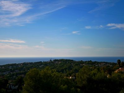 Vista panorámica de Benimeit, Moraira, con el mar Mediterráneo al fondo y cielo azul con nubes.