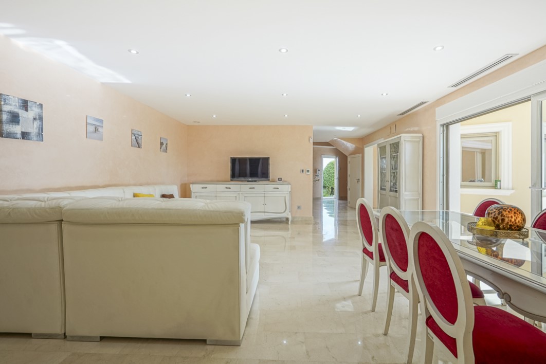 Salón-comedor de planta abierta con suelos de mármol pulido, iluminación empotrada y acceso directo a la terraza mediante amplios ventanales correderos.