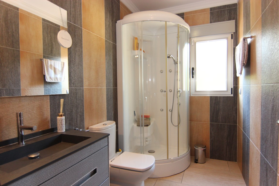 Baño contemporáneo con cabina de ducha semicircular, paredes de gres en tonos naturales y mueble de lavabo moderno con grifería monomando.