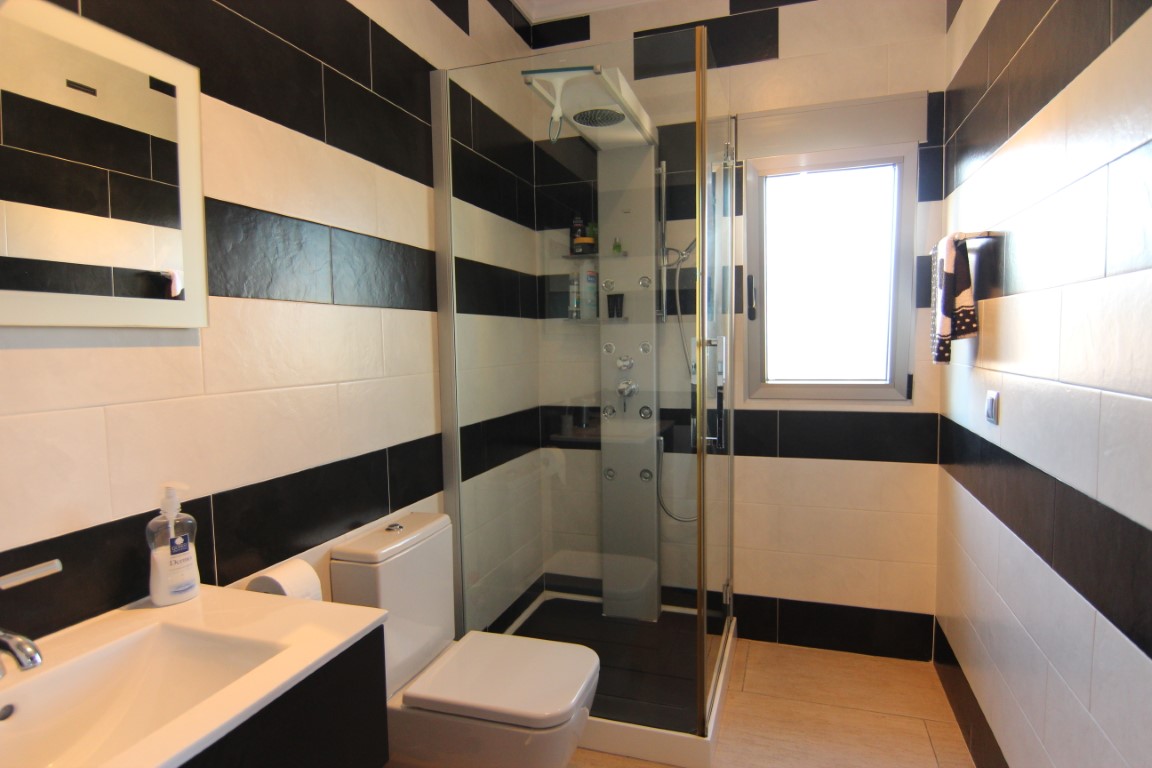 Cuarto de baño con diseño contemporáneo de azulejos en blanco y negro, equipado con cabina de ducha de hidromasaje y ventana exterior.