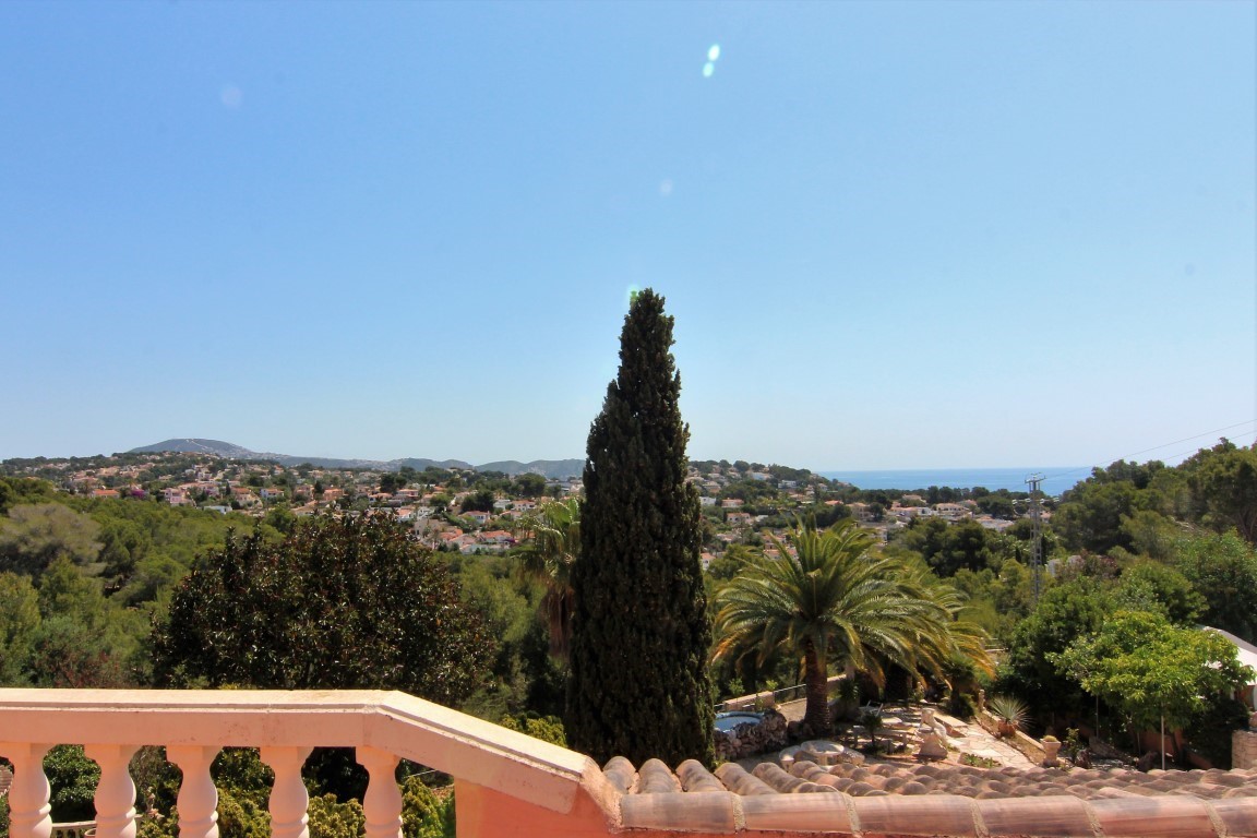 Vista panorámica desde la terraza superior con balaustrada clásica, mostrando el entorno residencial, vegetación mediterránea y el mar en el horizonte.