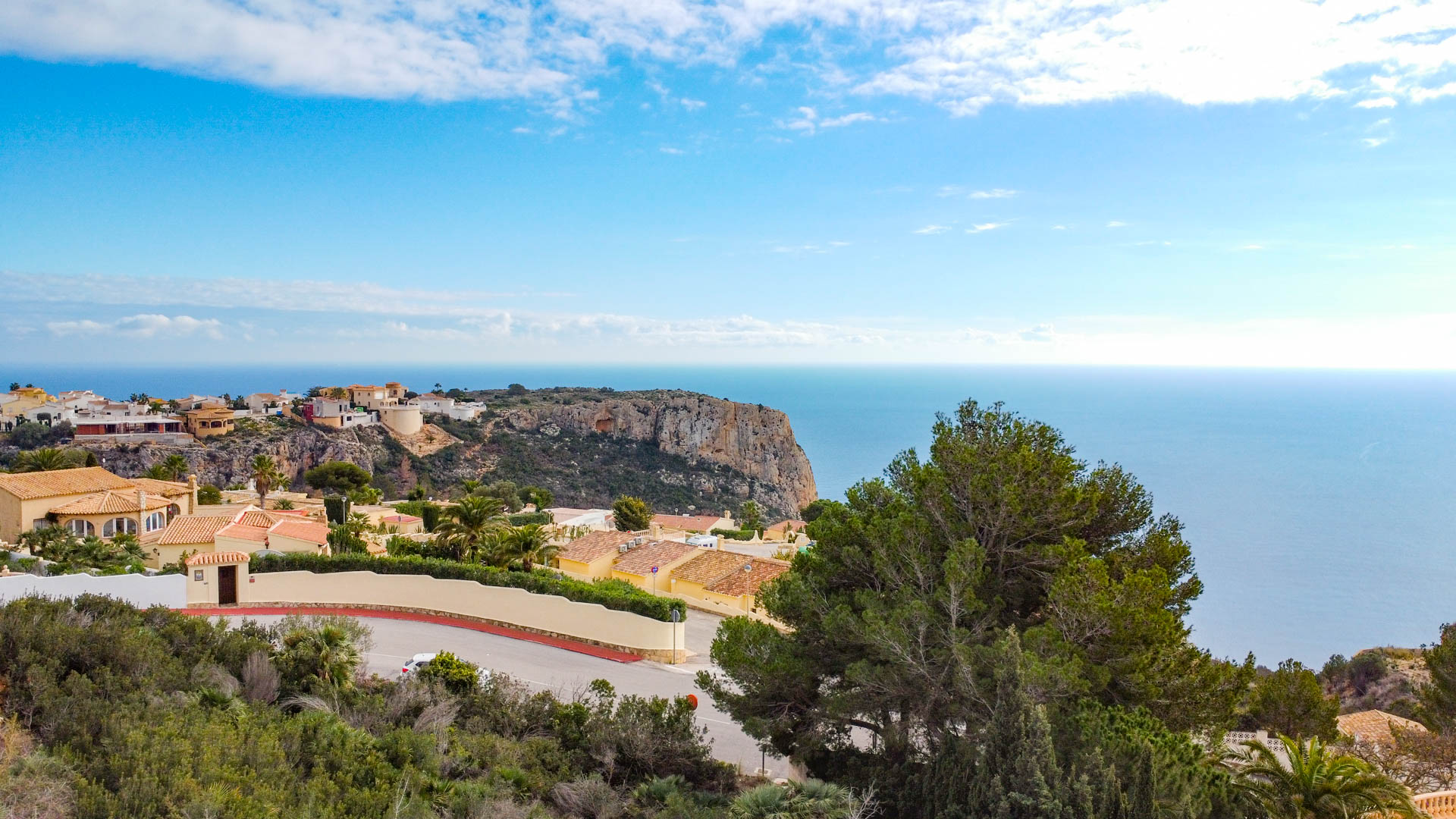 Vista panorámica desde Cumbre del Sol que muestra la costa mediterránea, acantilados escarpados y villas residenciales rodeadas de vegetación autóctona.