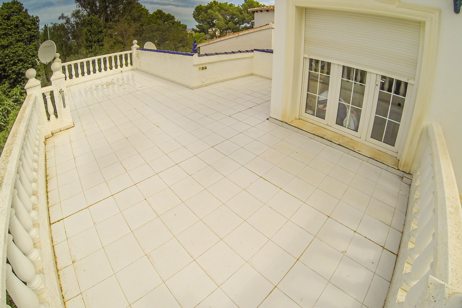 Amplia terraza con suelo de baldosas blancas y barandilla de balaustres, ideal para disfrutar del aire libre.