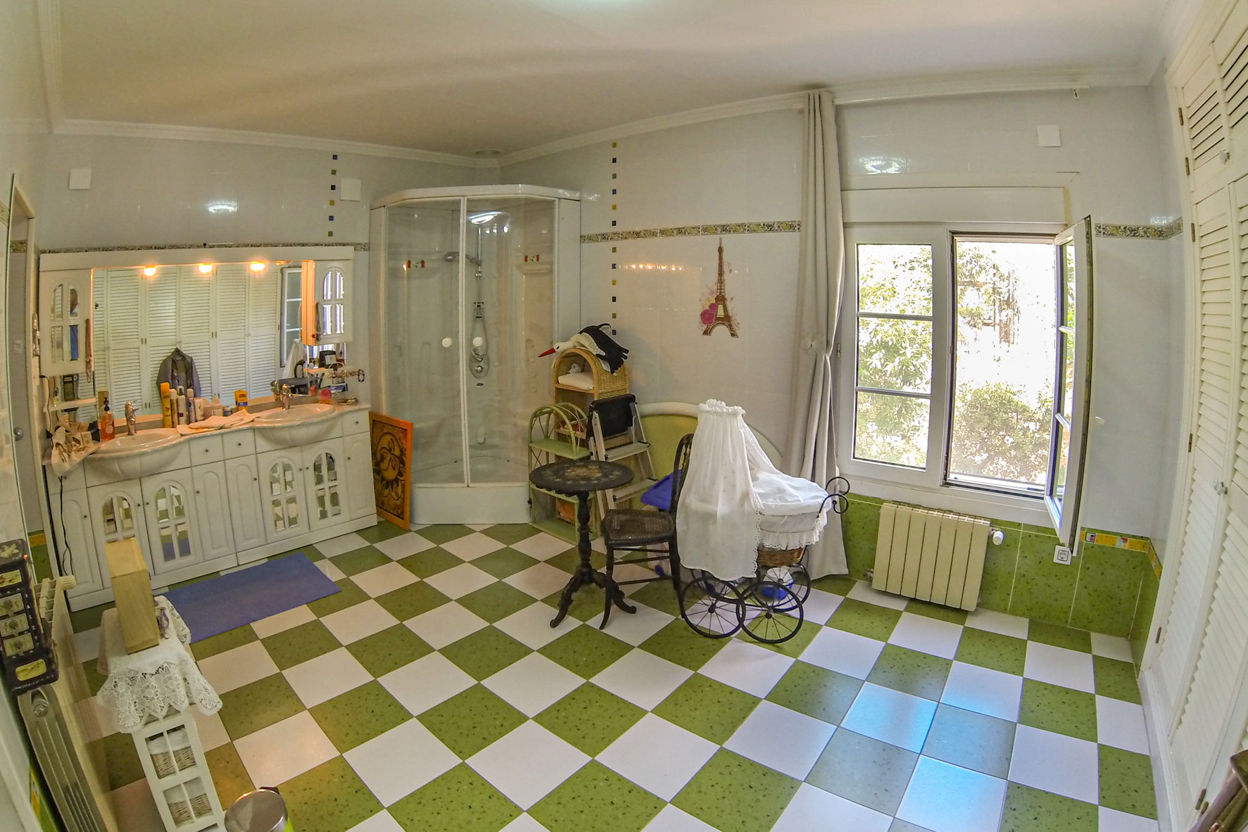 Cuarto de baño con suelo de baldosas a cuadros verdes y blancos, ducha esquinera y tocador doble con armarios blancos.