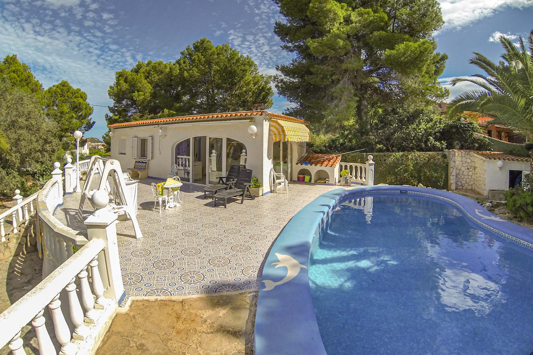 Vista de la piscina privada con mosaicos azules y la casita de piscina con toldo amarillo.