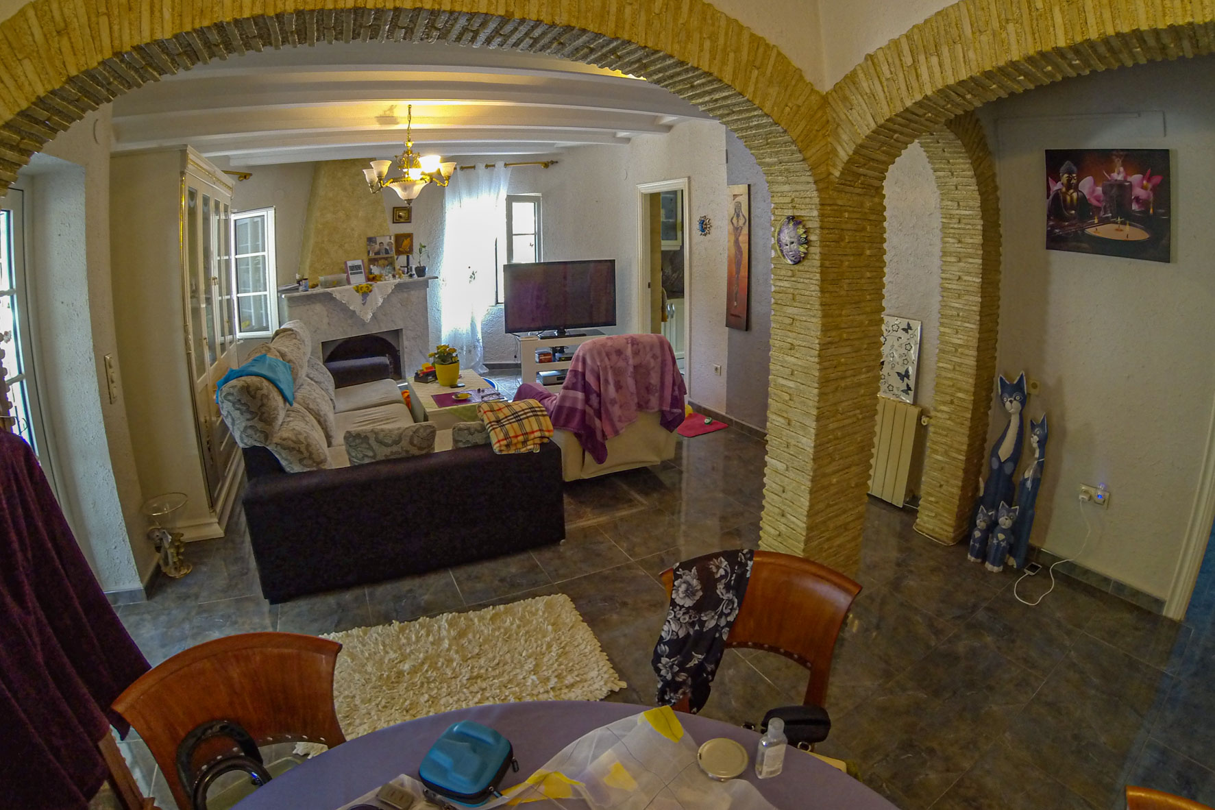Vista del salón con arcos de piedra, chimenea de mármol y mobiliario ecléctico.