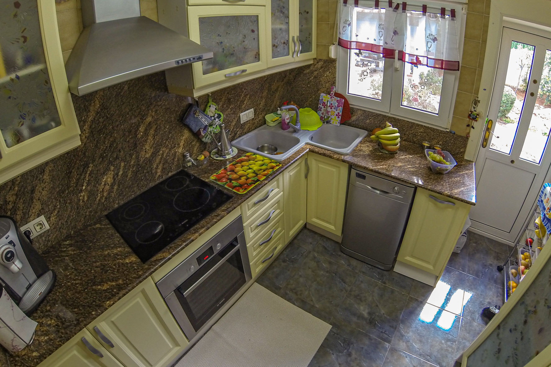 Vista elevada de la cocina con encimeras de granito marrón, electrodomésticos de acero inoxidable y muebles de color crema.