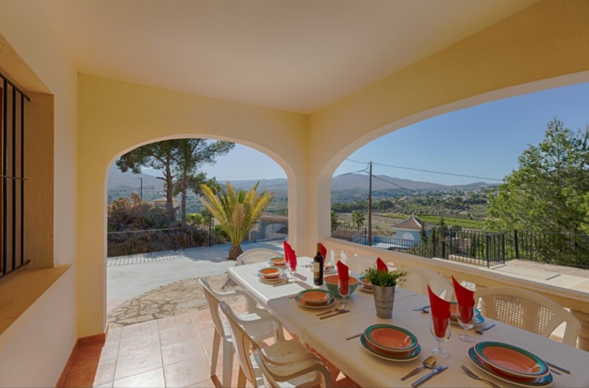 Terraza cubierta con arcos tradicionales, zona de comedor exterior y vistas panorámicas despejadas hacia el valle y las montañas circundantes.