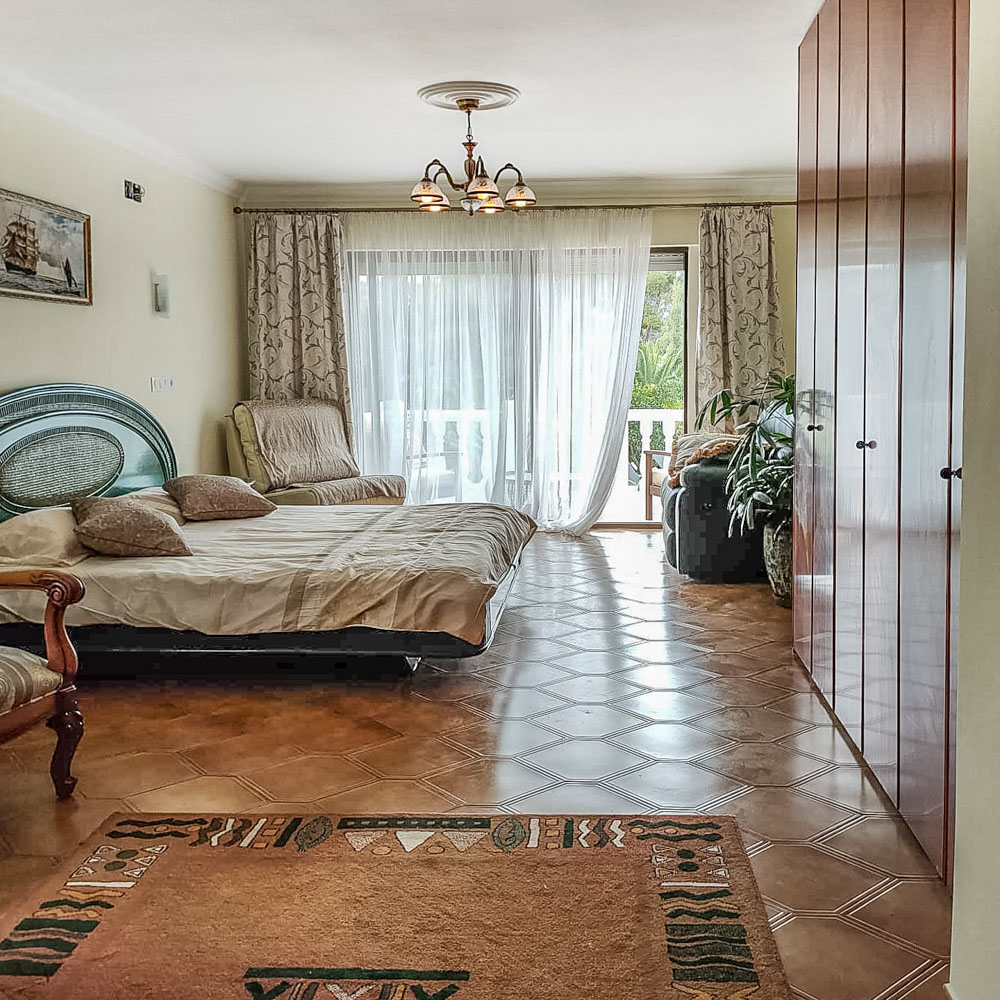 Dormitorio luminoso con armarios empotrados de madera, suelo de gres cerámico y acceso directo a una terraza privada a través de grandes ventanales.