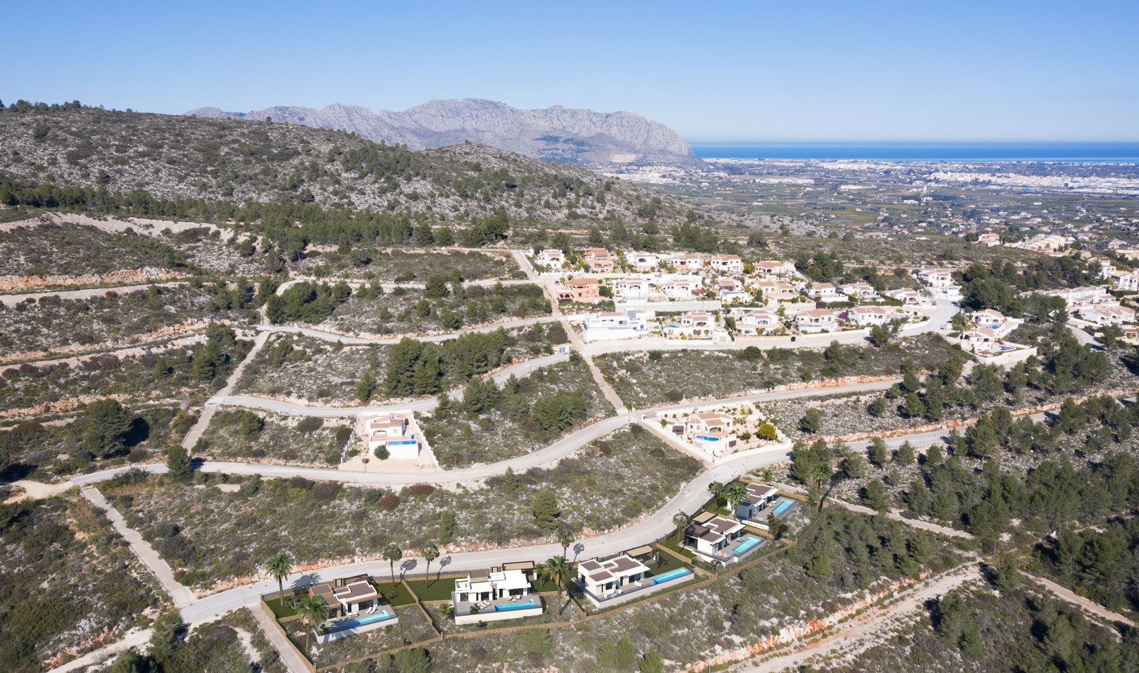 Vista aérea de la urbanización en Pedreguer, mostrando la ubicación de los chalets modernos con piscina y las vistas panorámicas hacia la costa y la montaña.
