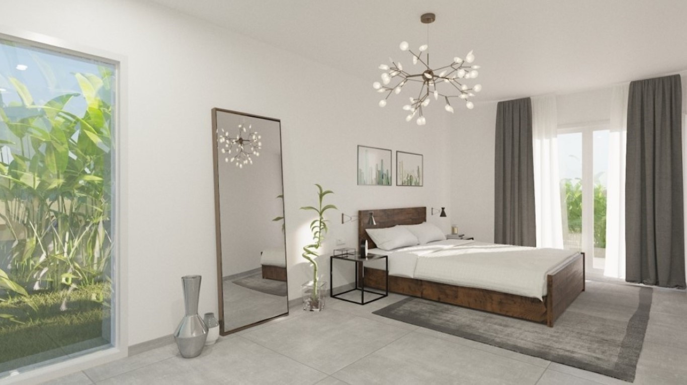 Dormitorio principal con cama de madera oscura, lámpara de diseño tipo rama y grandes ventanales que ofrecen luz natural y vistas al jardín.