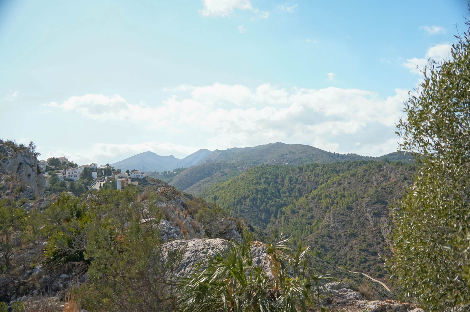 Vista panorámica de La Sella con casas blancas y montañas boscosas.