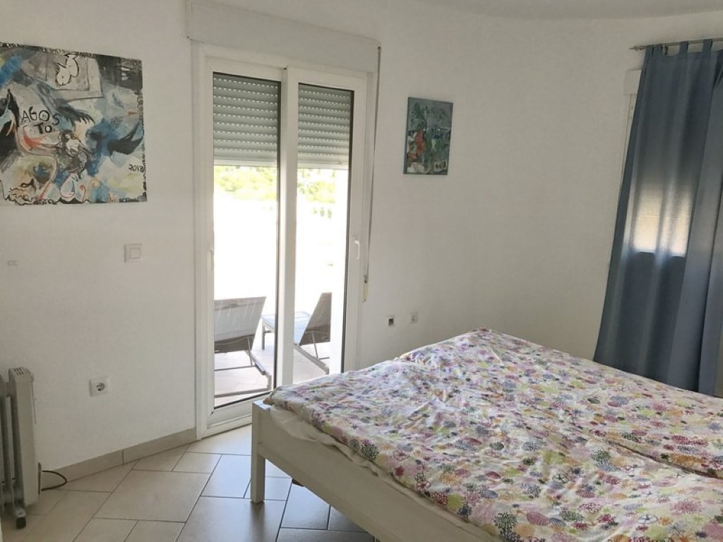 Dormitorio luminoso con suelos cerámicos y acceso directo a una terraza privada a través de una puerta corredera con persiana integrada.