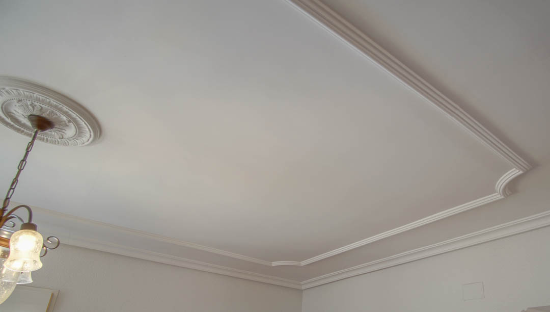 Detalle del techo con molduras decorativas de escayola y un rosetón clásico que realza la elegancia de los acabados interiores de la villa.